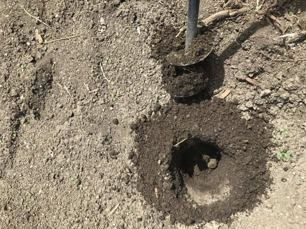 Auger next to drilled hole in dirt