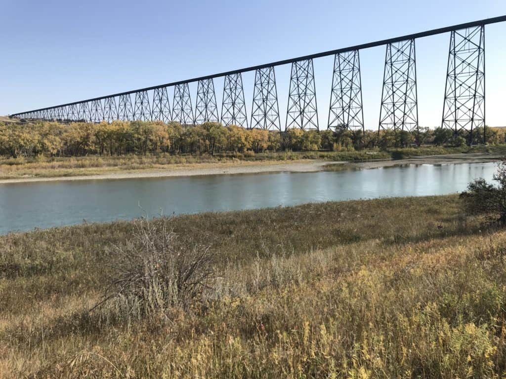View of fall colored trees, Old Man River and High Level Bridge from path near Elizabeth Hall Wetlands in Lethbridge, Alberta