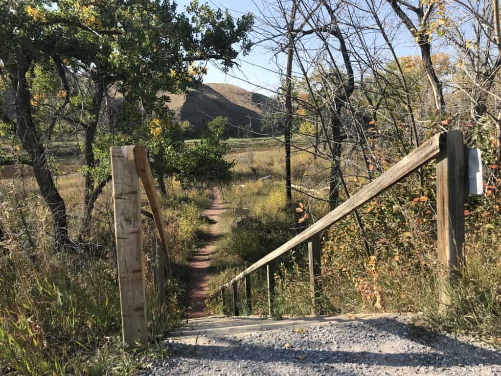 View of rustic stairs leading down to red shale pathway in Elizabeth Hall Wetlands, Lethbridge, Alberta